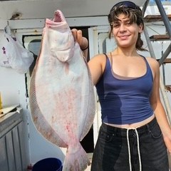 Person holding a large flat fish on a boat.