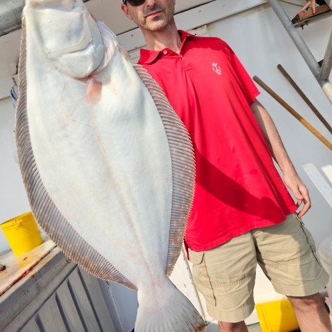 Man holding a large fish on a boat deck.